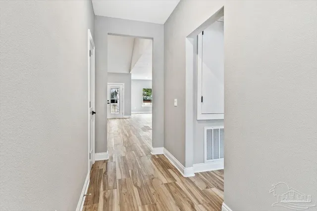 a view of a hallway with wooden floor and a bathroom