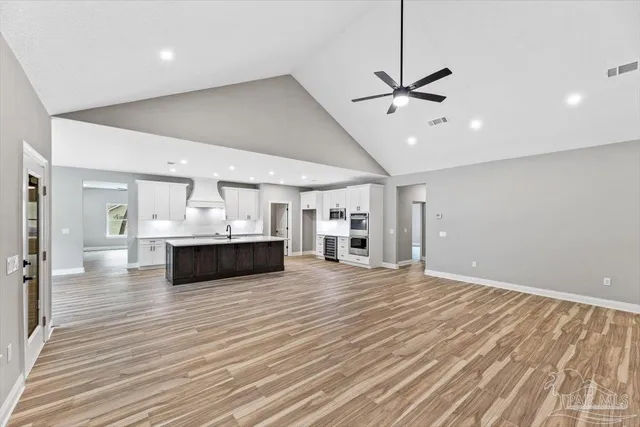 a large white kitchen with kitchen island a sink stainless steel appliances and cabinets