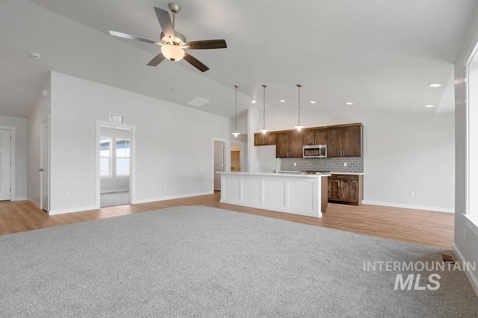 1340 Dawn Street Weiser, ID 83672 - Photo 8 of 32 Unfurnished living room featuring light wood finished floors, a ceiling fan, vaulted ceiling, light carpet, and recessed lighting