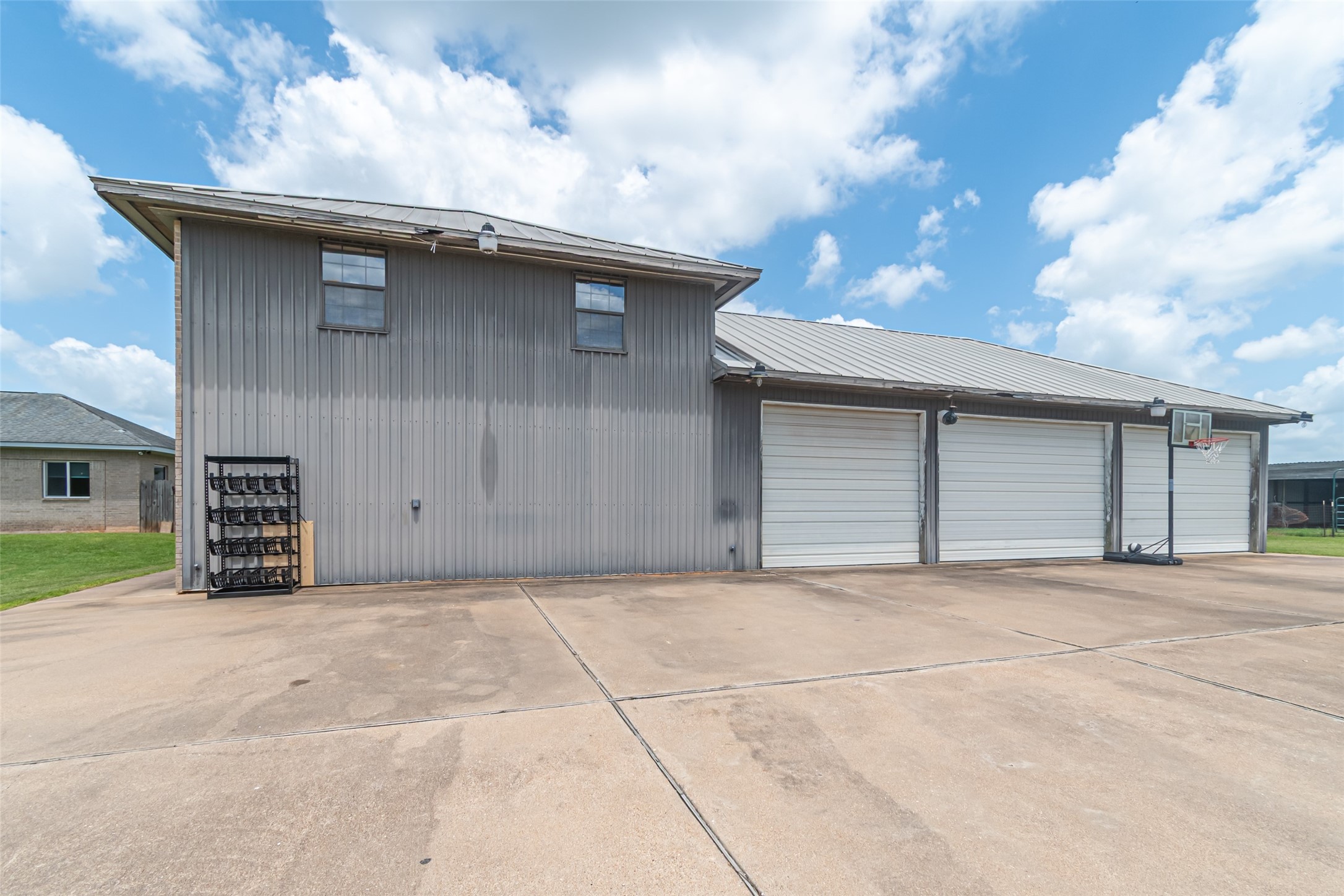 38766 Wyatt Chapel Road Hempstead, TX 77445 - Photo 34 of 45 Spacious garage with five roll-up doors, a wide concrete driveway, and a durable metal exterior. Features ample downstairs storage, full bath, half bath, and an upstairs garage apartment.