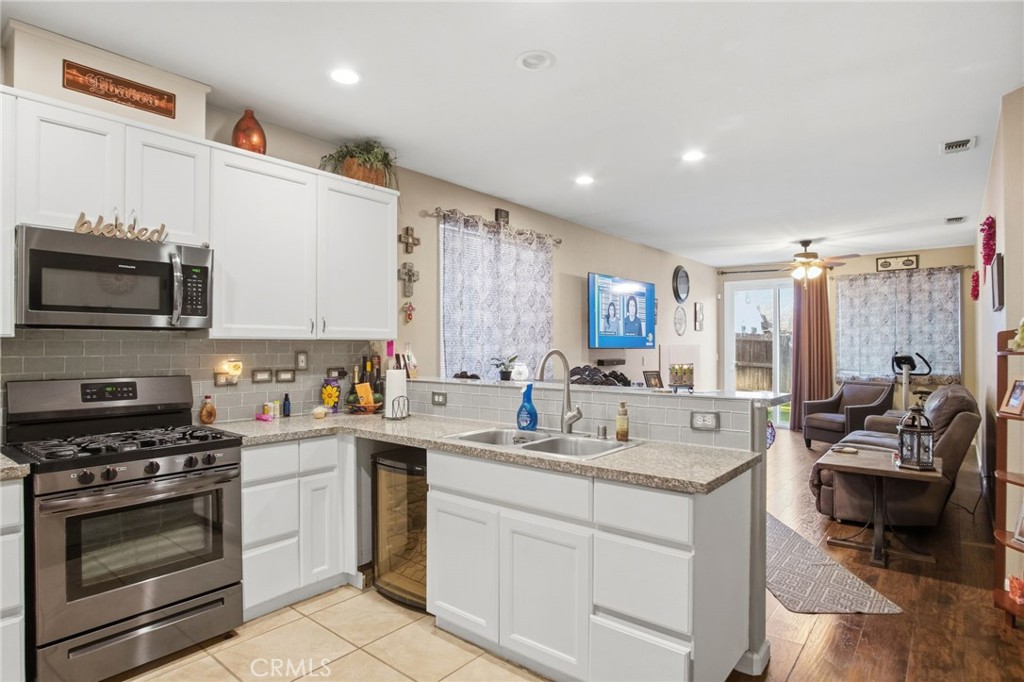 450 Beckman Way Merced, CA 95348 - Photo 9 of 22 a kitchen with stainless steel appliances kitchen island granite countertop a sink dishwasher stove and white cabinets with wooden floor