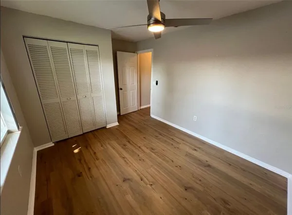 an empty room with wooden floor cabinet and windows