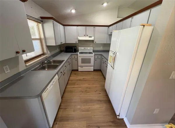 a kitchen with white cabinets and refrigerator