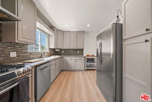 a kitchen with stainless steel appliances granite countertop a refrigerator and a stove top oven