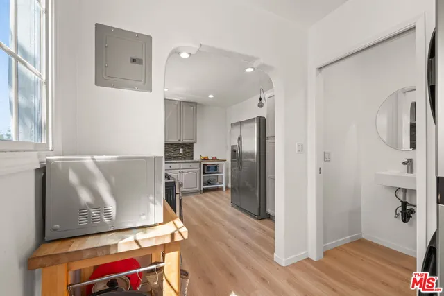 a living room with stainless steel appliances furniture a refrigerator and wooden floor