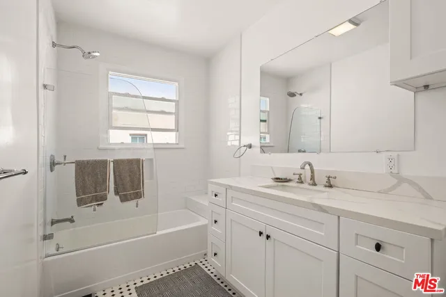 a bathroom with a tub sink double vanity granite and a shower