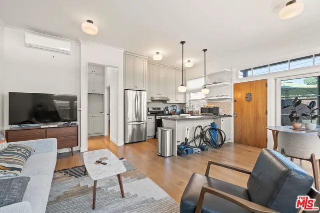 a kitchen with stainless steel appliances kitchen island granite countertop a refrigerator a stove a microwave oven a dining table and chairs with wooden floor