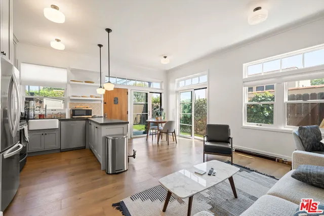 a living room with furniture kitchen view and large windows