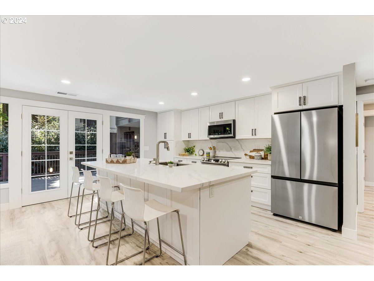 4820 Southwest Marigold Street Portland, OR 97219 - Photo 4 of 34 a kitchen with stainless steel appliances refrigerator wooden floor dining table and chairs