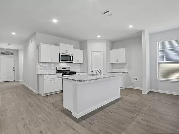 a kitchen with granite countertop a refrigerator stove top oven and sink