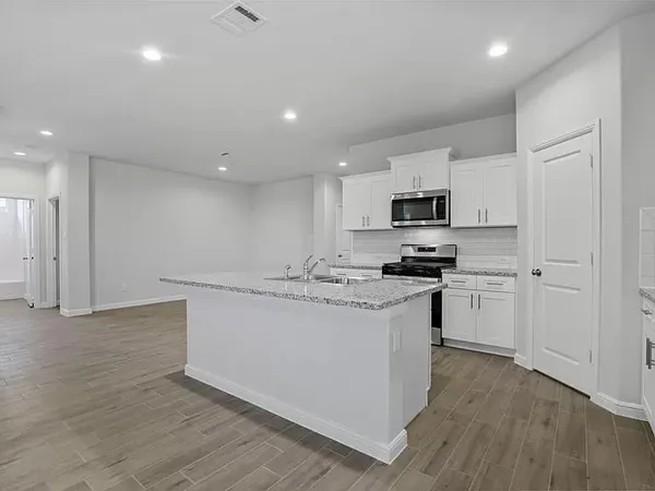 a kitchen with granite countertop white cabinets and stainless steel appliances