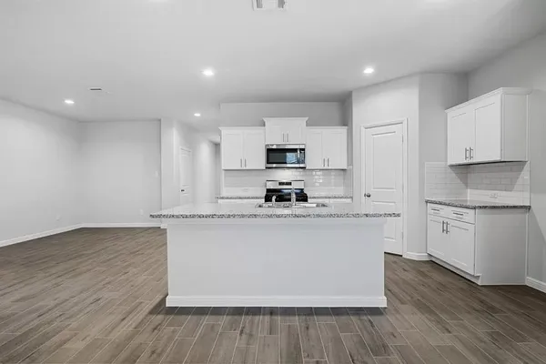 a kitchen with stainless steel appliances granite countertop a stove top oven a sink and white cabinets with wooden floor