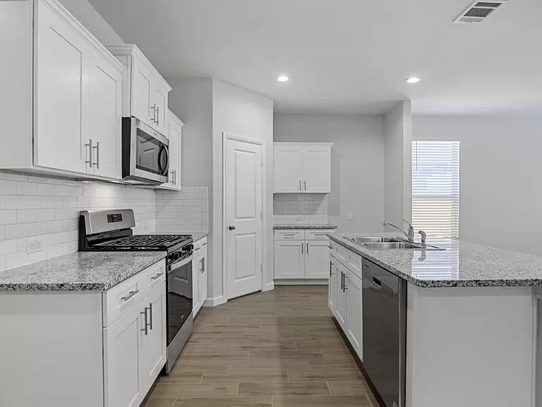 5229 Boulder Vly Drive Fort Worth, TX 76179 - Photo 8 of 39 a kitchen with stainless steel appliances granite countertop a stove top oven a sink a refrigerator and white cabinets