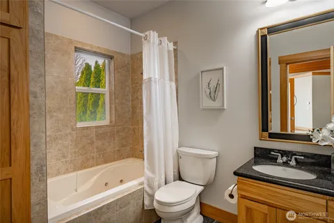 a bathroom with a bathtub sink vanity mirror and toilet