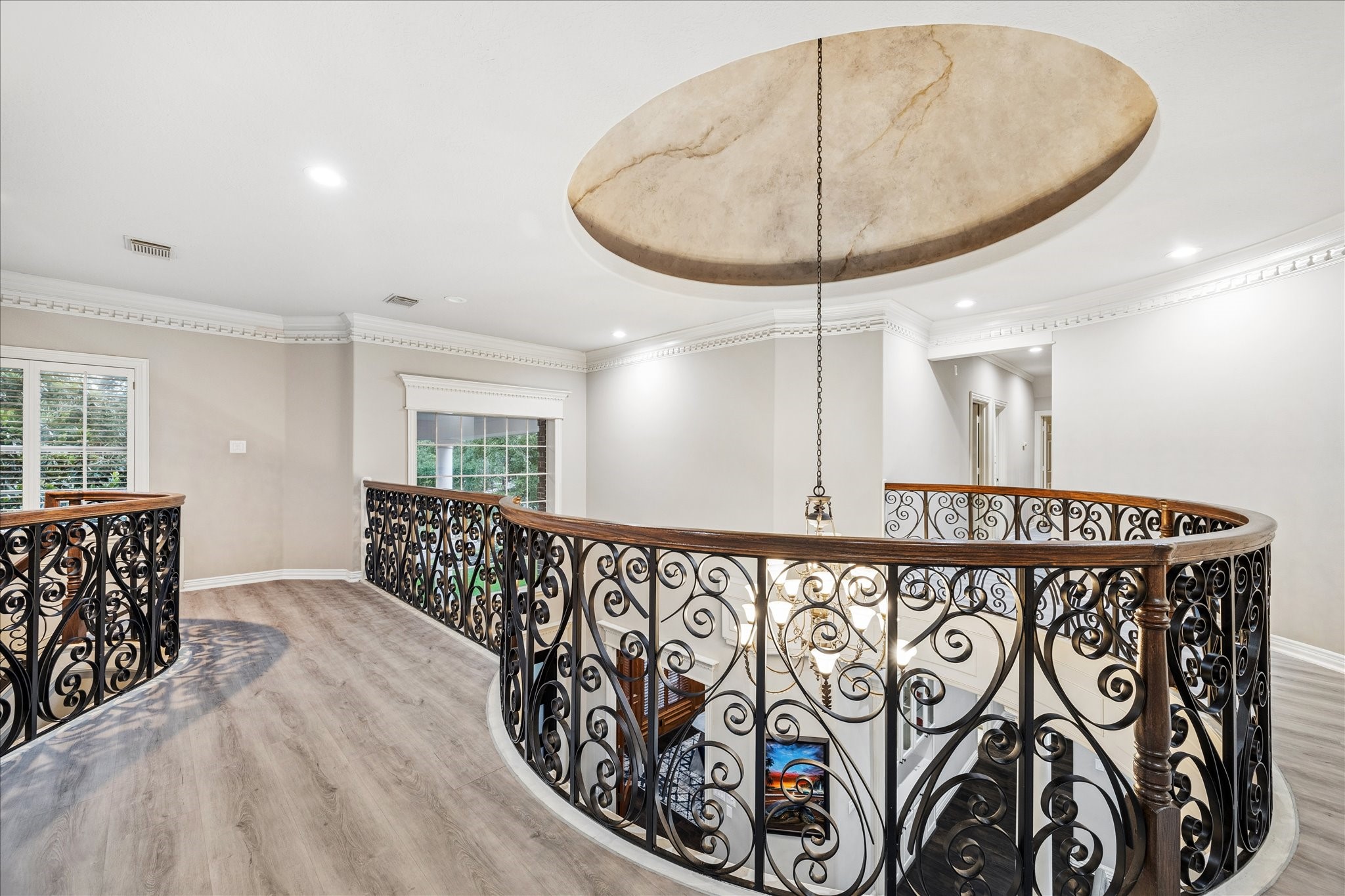 35 North Regent Oak Spring, TX 77381 - Photo 32 of 43 An impressive architectural feature of the home, this second-floor gallery showcases stunning wrought-iron railings, elegant millwork, and a dramatic open view of the grand foyer below. The curved design creates a sense of sophistication and openness, while the beautiful chandelier and decorative ceiling detail add a touch of timeless elegance. A striking transition space that connects the upstairs bedrooms and living areas with style and character.