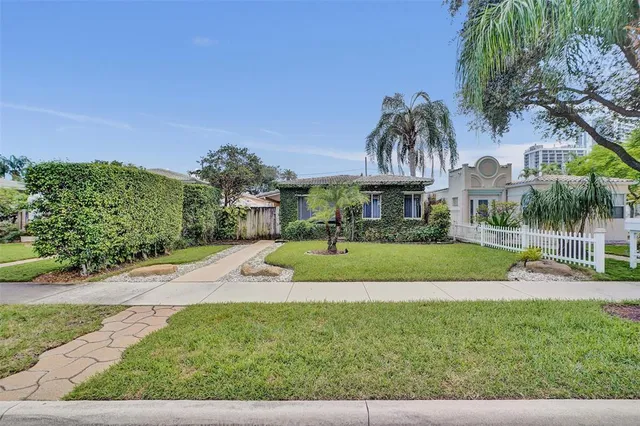 a front view of a house with a yard and potted plants