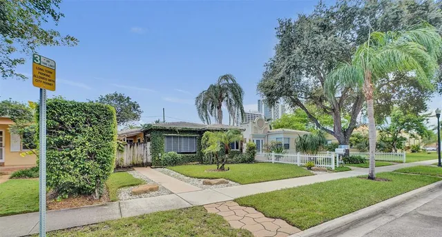 a view of a white house with a yard and potted plants