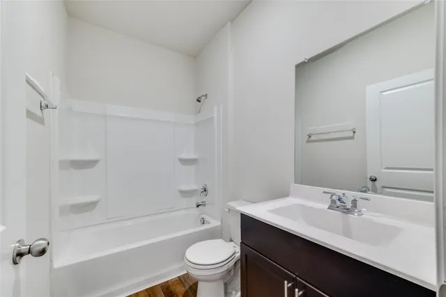 a bathroom with a sink a toilet a mirror a bathtub and shower