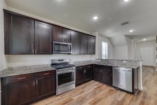 a kitchen with stainless steel appliances granite countertop wooden cabinets granite counter tops and a stove