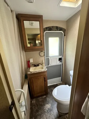 a bathroom with a granite countertop toilet sink and mirror