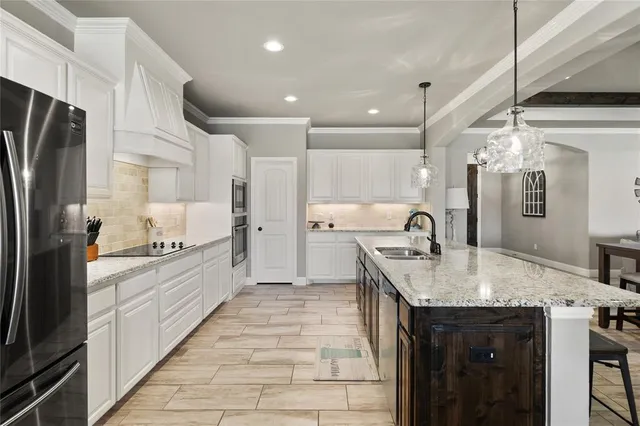 a large kitchen with granite countertop a sink refrigerator and cabinets