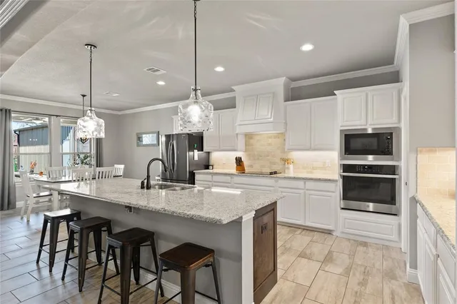 a kitchen with kitchen island granite countertop a sink a center island and appliances