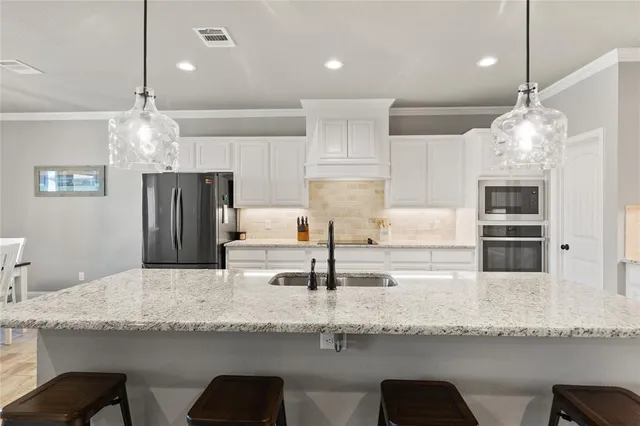 a kitchen with stainless steel appliances granite countertop a sink refrigerator and microwave