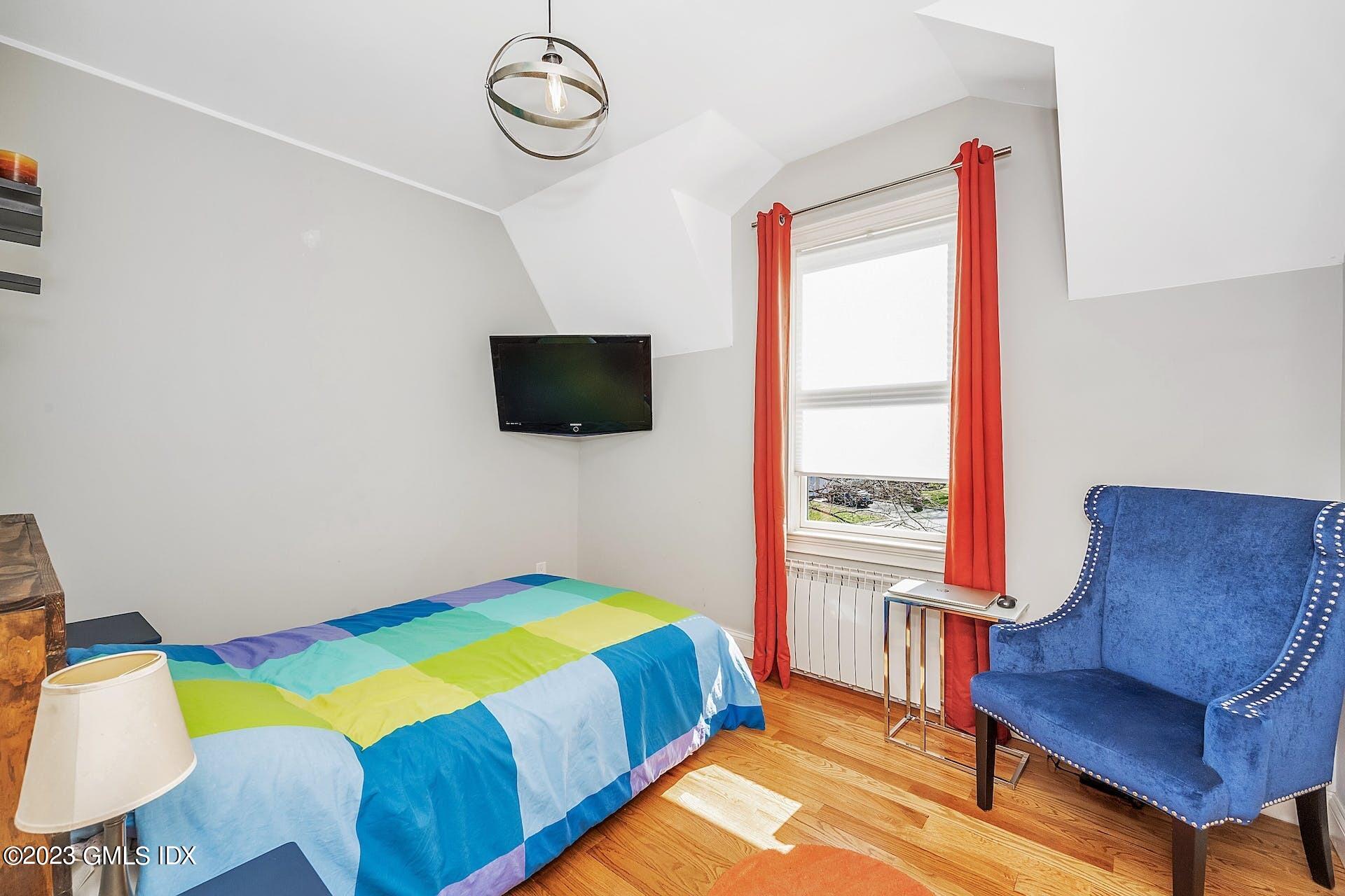 58 Upland Road Stamford, CT 06906 - Photo 22 of 32 a bedroom with a bed a window and a flat screen tv