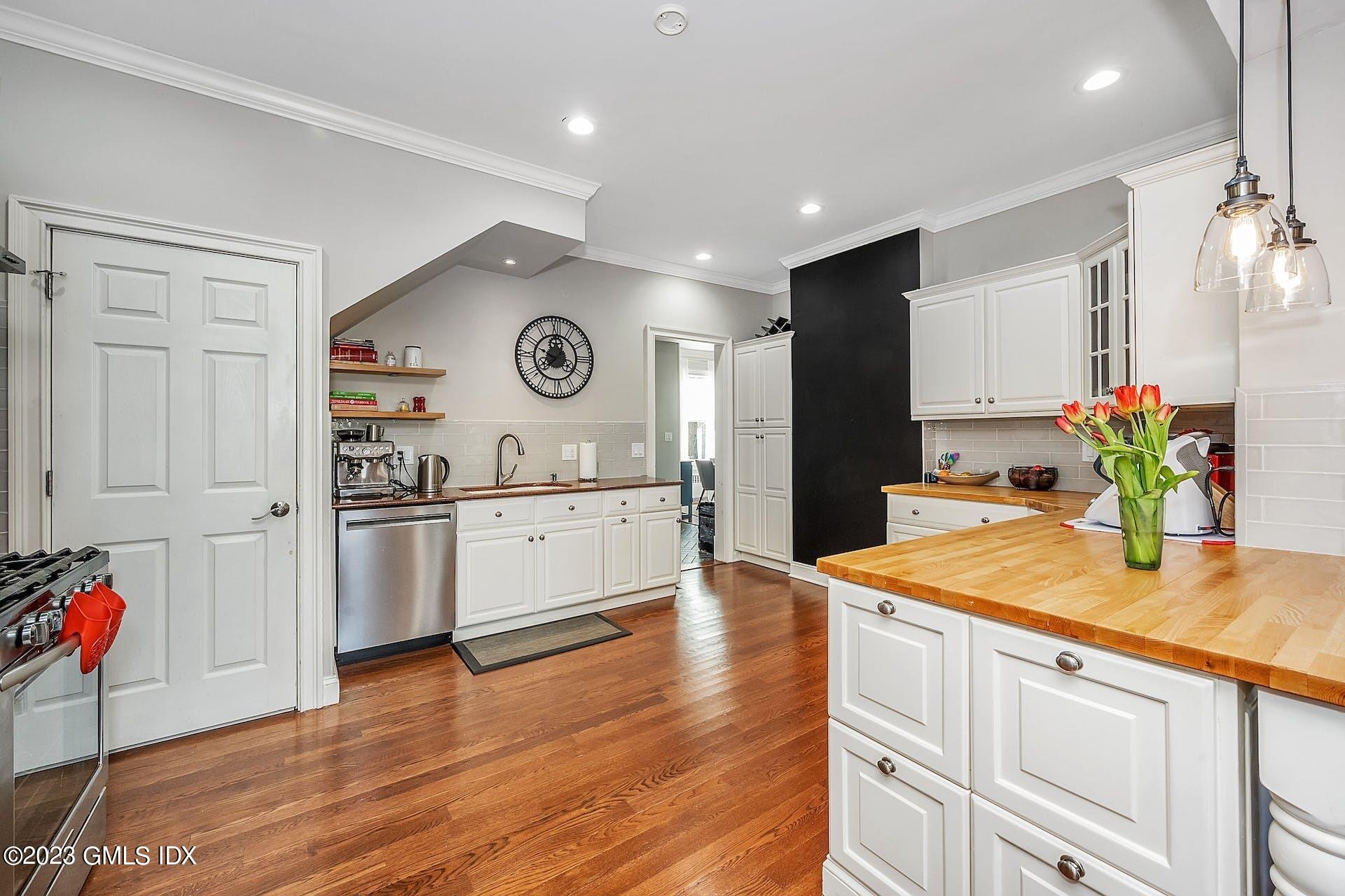 58 Upland Road Stamford, CT 06906 - Photo 9 of 32 a kitchen with stainless steel appliances kitchen island granite countertop a refrigerator a sink dishwasher and white cabinets with wooden floor