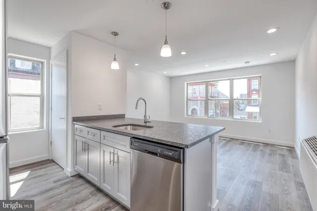 a kitchen with stainless steel appliances granite countertop a sink a window and wooden floor