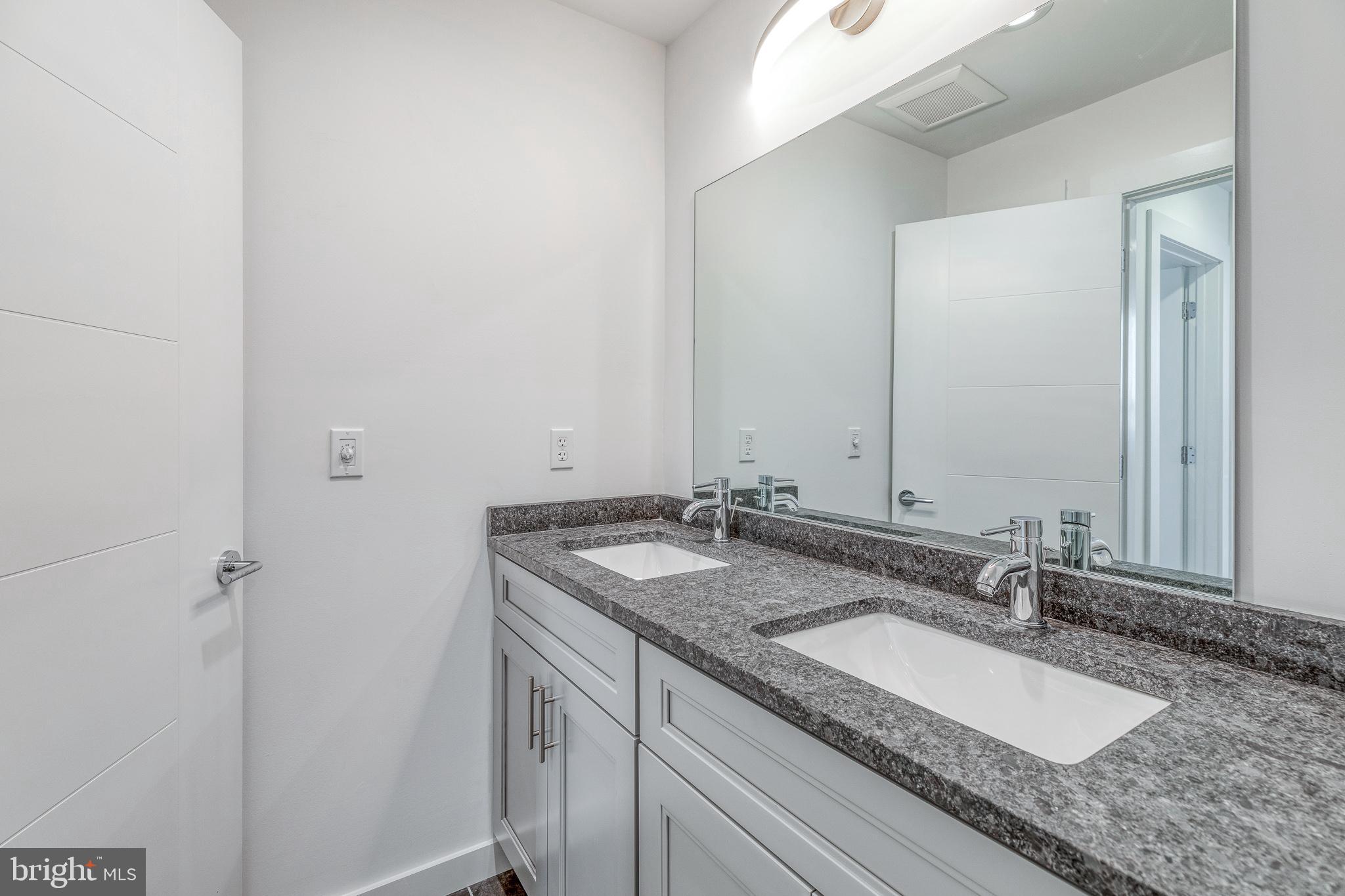 751 North 43rd Street, Unit 302 Philadelphia, PA 19104 - Photo 12 of 17 a bathroom with a granite countertop sink and a mirror