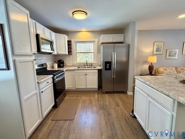 a kitchen with a refrigerator a sink dishwasher stove and wooden floor