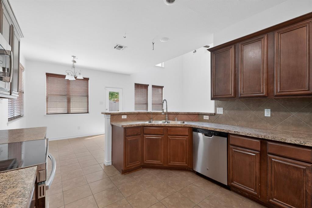 426 Harding Lane Lavon, TX 75166 - Photo 11 of 40 Kitchen featuring wood-finish cabinetry, speckled countertops, tile flooring, stainless steel dishwasher, and an undermount sink
