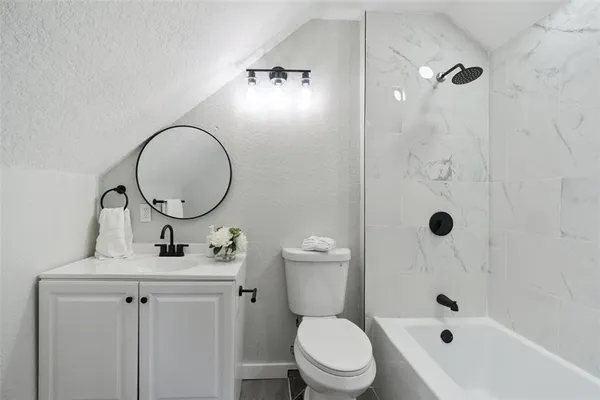 a bathroom with a toilet a sink a mirror a bathtub and shower