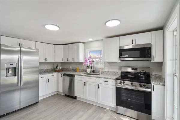 a kitchen with granite countertop a sink stainless steel appliances and cabinets