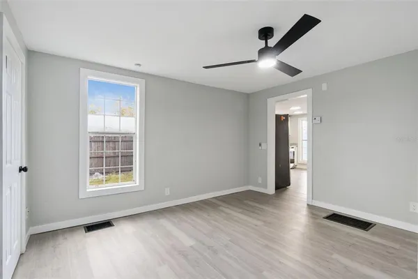 a view of an empty room with a window and wooden floor