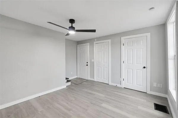 a view of empty room with wooden floor and ceiling fan