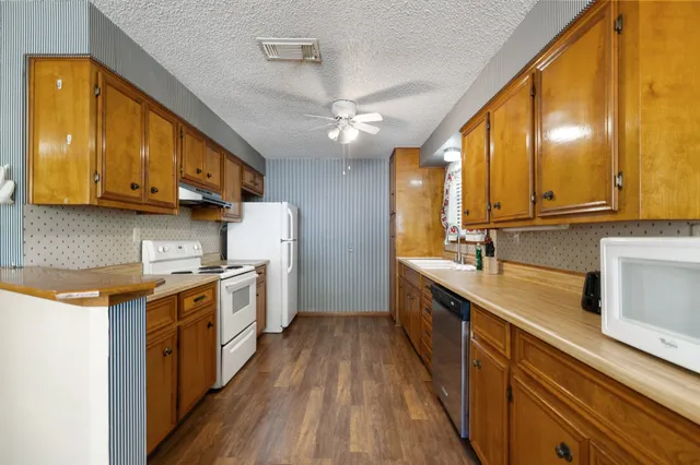 a large kitchen with stainless steel appliances granite countertop a sink a stove and a wooden floors