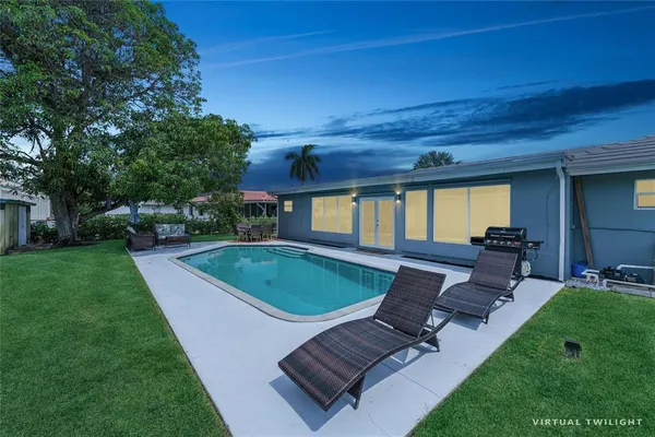 a view of a backyard with couches plants and large tree