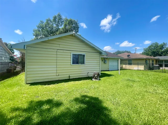 a backyard of a house with plants and large tree