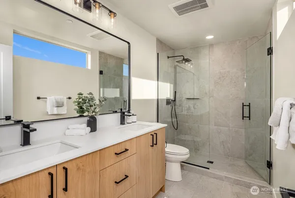 a bathroom with a shower sink vanity mirror and toilet