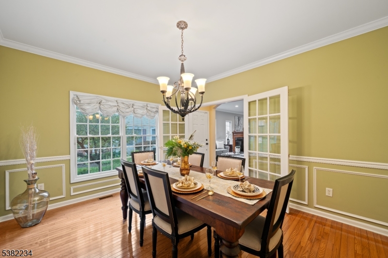 26 Chestnut Court Cedar Grove, NJ 07009 - Photo 17 of 43 a dining room with wooden floor a chandelier a wooden table and chairs