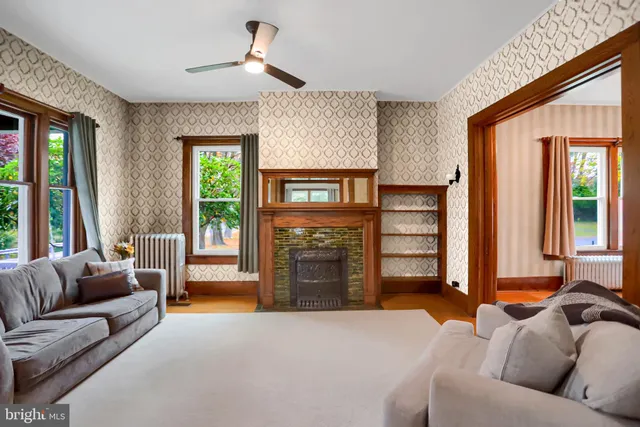a living room with furniture and a large mirror next to a window