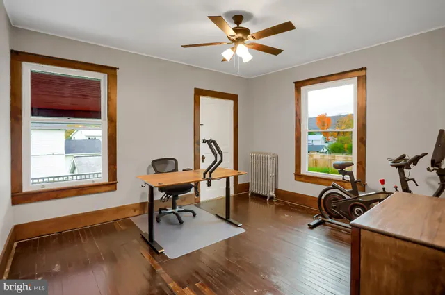 a view of an empty room with wooden floor and windows