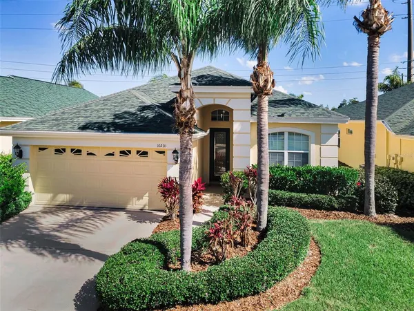 front view of a house with a yard and palm trees