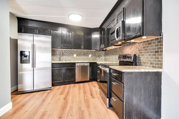 a kitchen with stainless steel appliances granite countertop a sink a stove and a refrigerator
