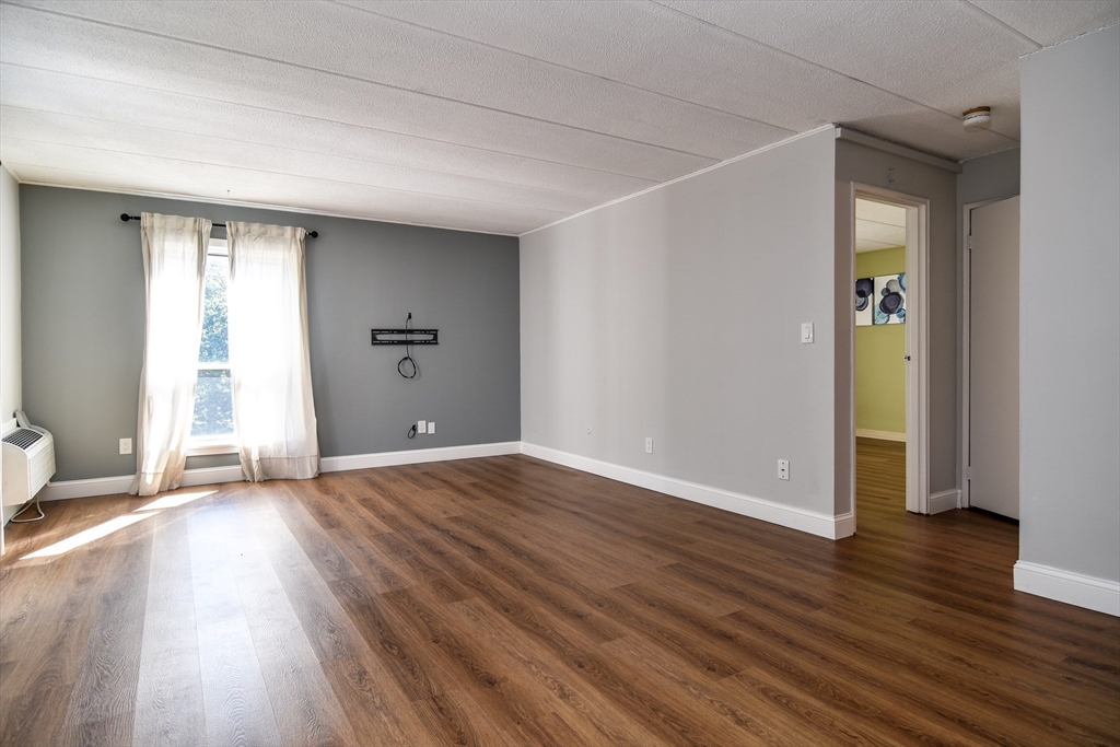 147 Turner Road, Unit 106 Holliston, MA 01746 - Photo 9 of 16 an empty room with wooden floor and windows