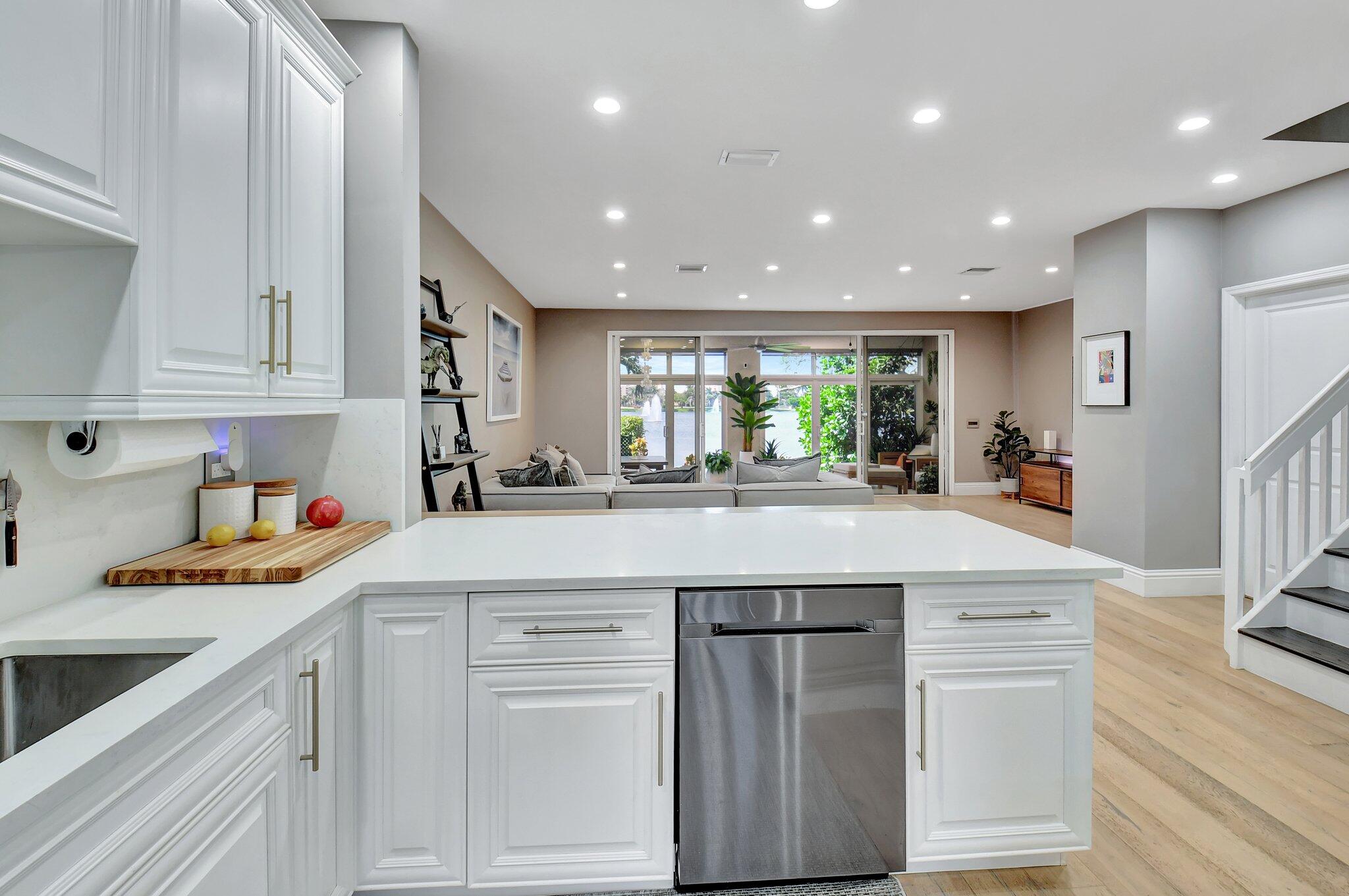 6795 Via Regina Boca Raton, FL 33433 - Photo 10 of 83 a kitchen with a sink dishwasher a stove and white cabinets with wooden floor