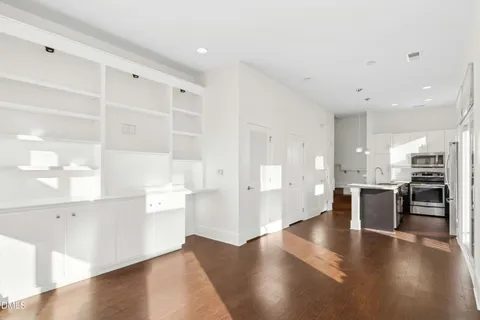a living room with furniture a flat screen tv and kitchen view