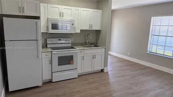 a kitchen with granite countertop white cabinets and white appliances